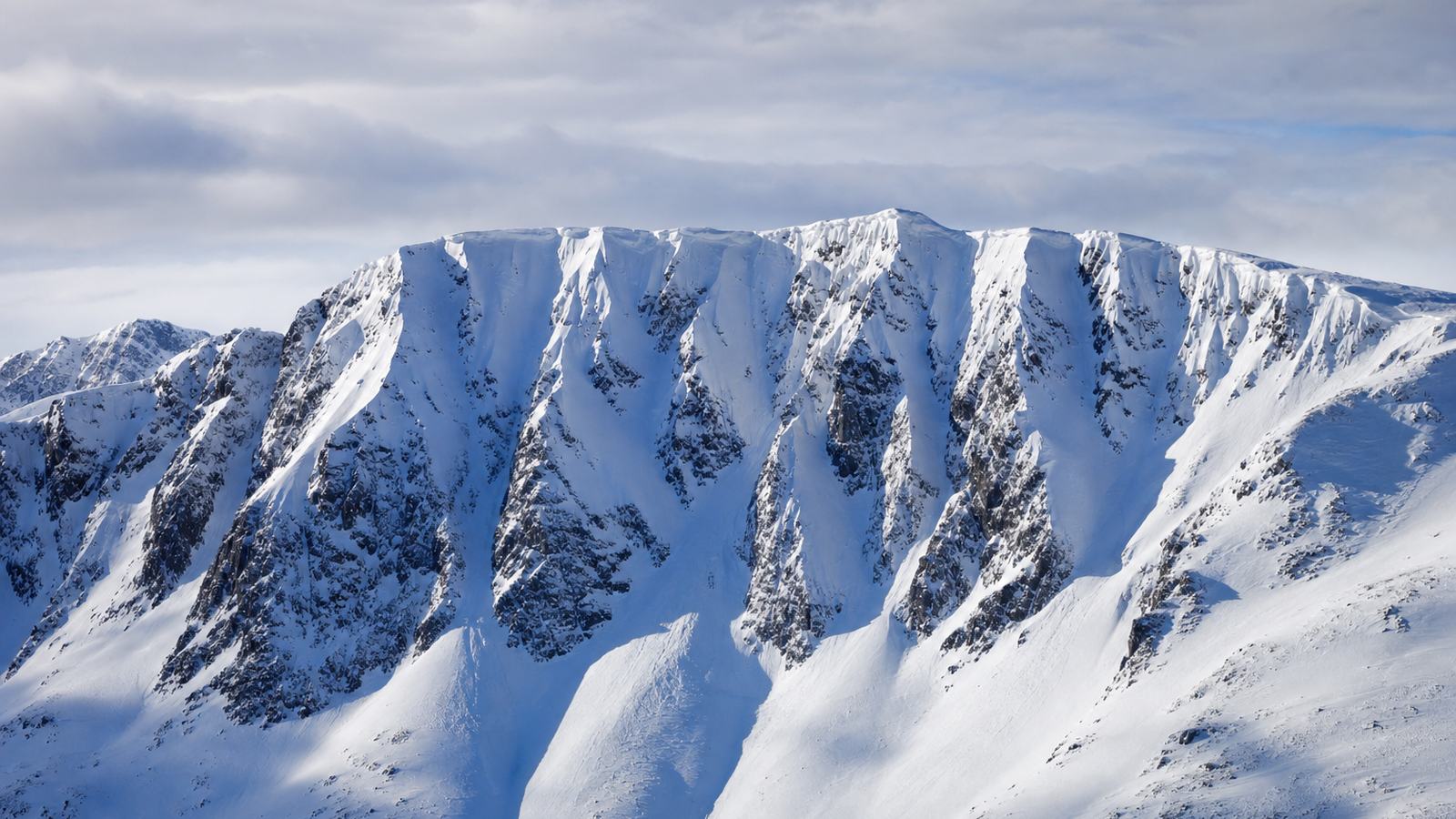 Skieurs de randonnée montant en file espacée sur une pente enneigée des Pyrénées, par temps clair